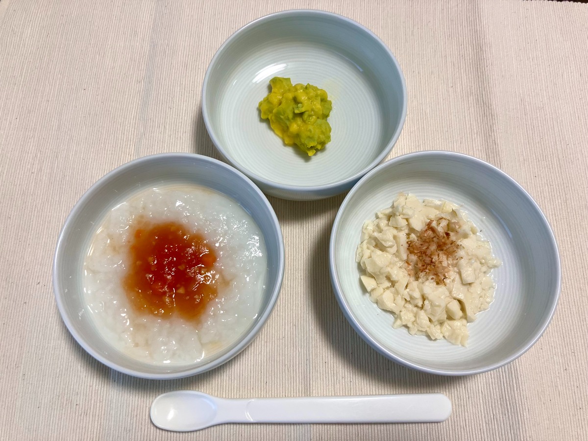 コープデリ白がゆにトマトコンソメソースをかけたもの、枝豆とコーンのマッシュ、絹豆腐にかつおぶしをかけたものを並べた離乳食